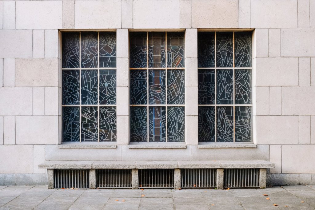 Three leaded windows in a plain stone wall
