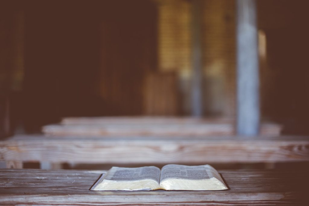 An open book resting on a wooden ledge in warm low light