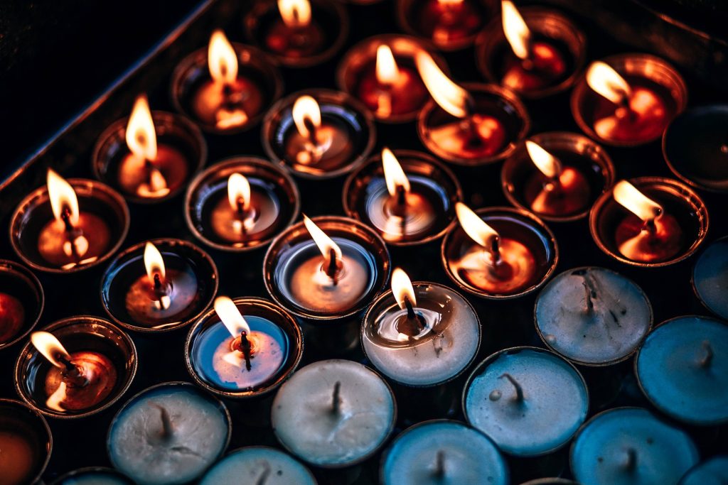 Rows of votive candles burning in blue and red holders