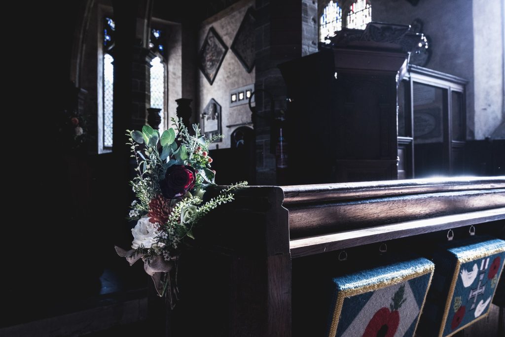 Flowers tied to the end of a dark wooden pew