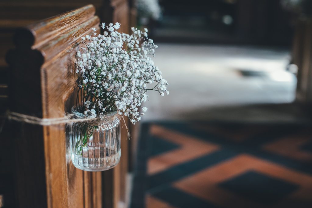 A jar of gypsophila hung from a wooden pew end